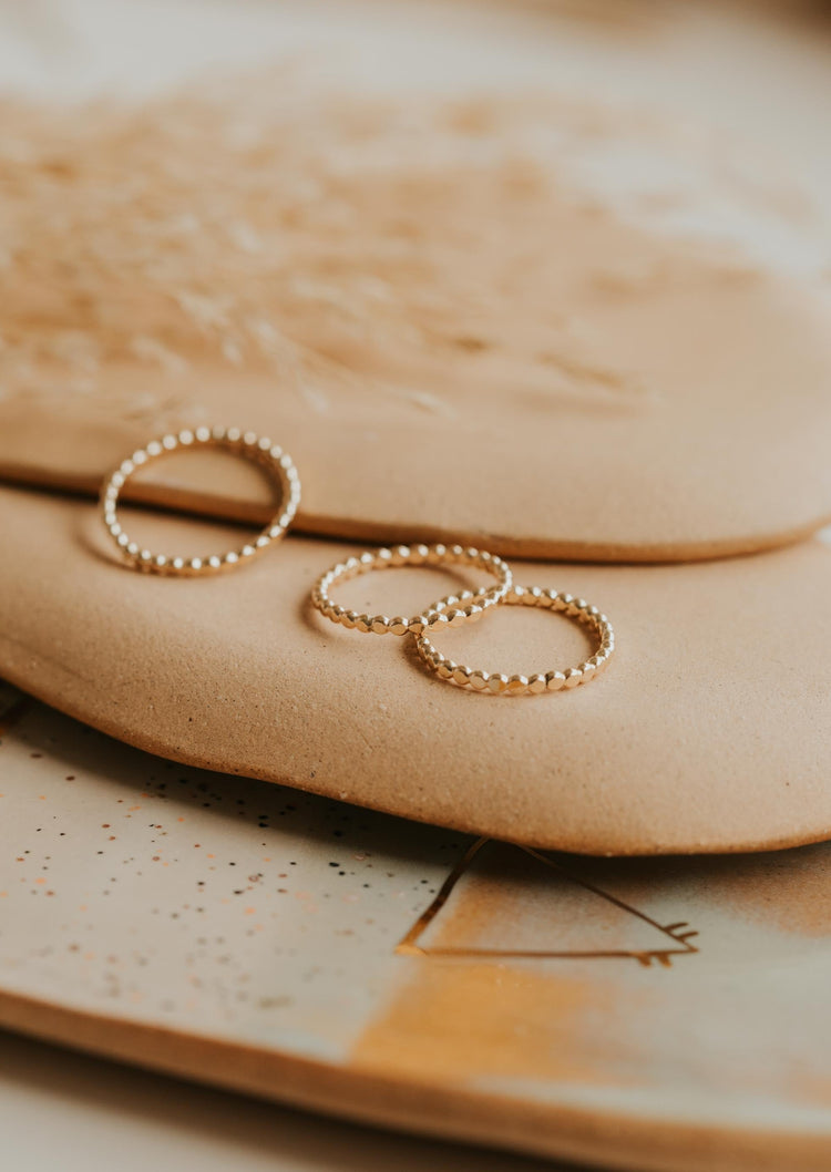 Three gold stacking rings in confetti band style laying flat on a jewelry tray by Hello Adorn.