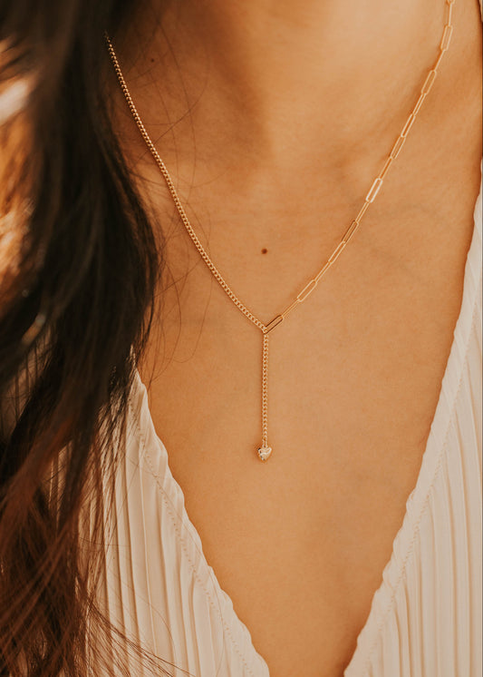 Gold necklace worn by a person with a blurred background