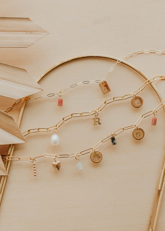 Gold chain with various charms on a beige background