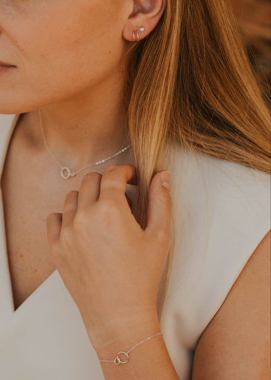 Close-up of a woman wearing a necklace and bracelet with a blurred background