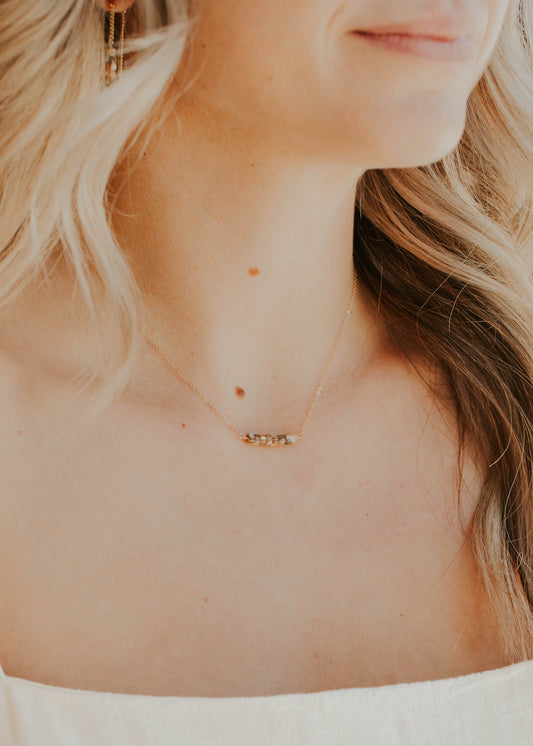 Close-up of a person wearing a delicate gold necklace with a small pendant.