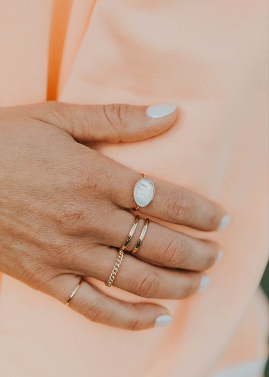 Hand wearing multiple rings on a soft peach background
