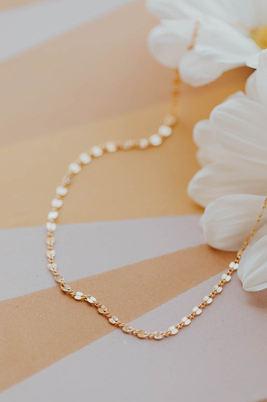 Pearl and gold chain necklace on a striped background with flowers