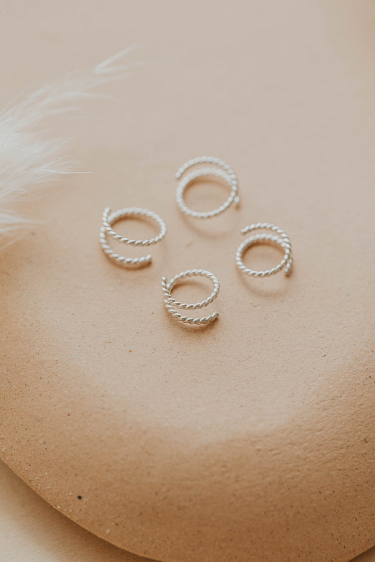 Sterling silver tiny twist earrings by Hello Adorn on a beige brown stone
