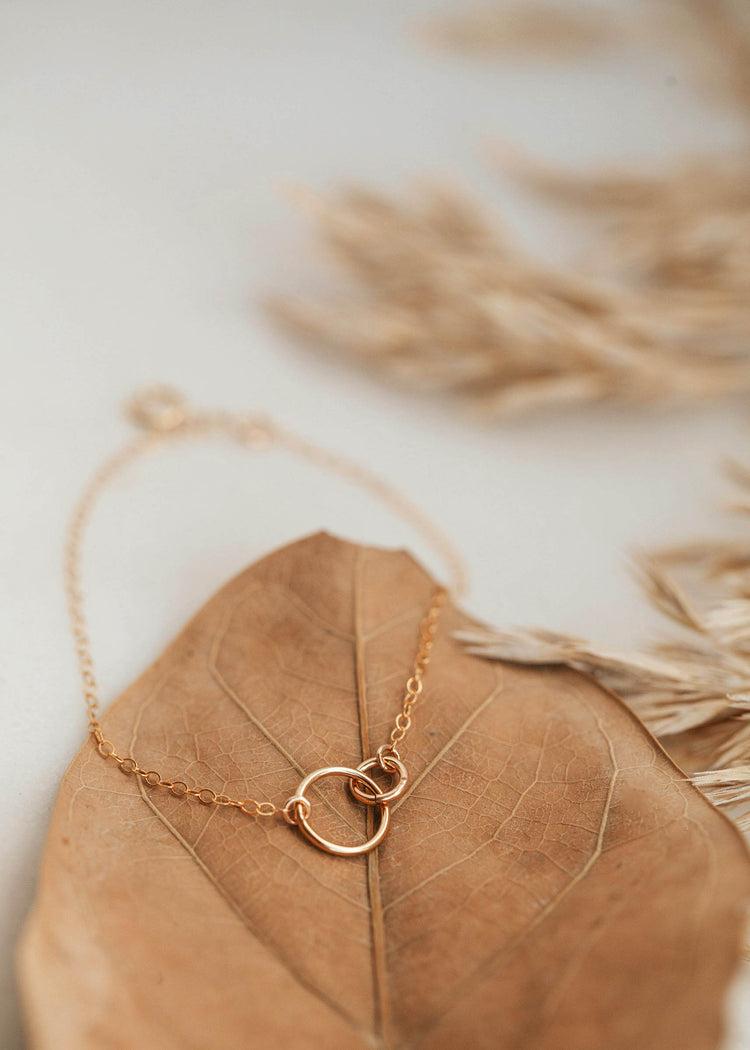 A chain bracelet with two interlocking circles attached to a dainty chain bracelet created by Hello Adorn in the Tiny Links Bracelet style.