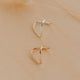 Two gold and silver hoop earrings on a beige background