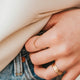 Close-up of a person buttoning a shirt with a blurred background