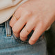 Close-up of a person wearing two gold rings on a blurred background