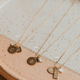 Gold necklaces with various pendants on a ceramic dish