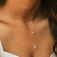 Close-up of a person wearing a delicate gold necklace with small stones.