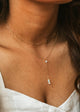 Close-up of a person wearing a delicate gold necklace with small stones.
