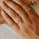 Close-up of hands wearing gold rings on a neutral background