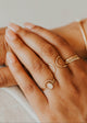 Close-up of hands wearing gold rings on a neutral background