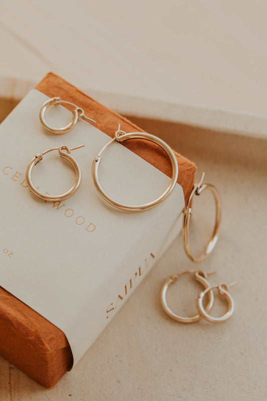 Thick gold hoops styled in an ear with small gold hoop earring and twist earrings by Hello Adorn in 14k gold fill.