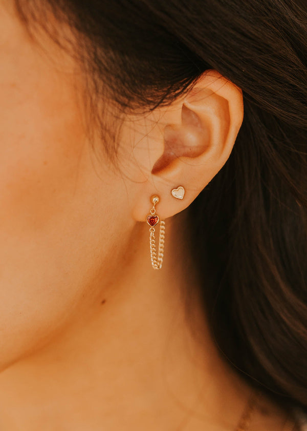 Close-up of a person wearing gold hoop earrings with a blurred background