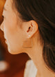 Close-up of a person wearing a heart-shaped earring with a blurred background