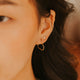 Close-up of a person wearing a gold hoop earring with a blurred background