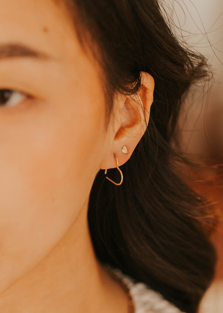 Close-up of a person wearing a gold hoop earring with a blurred background