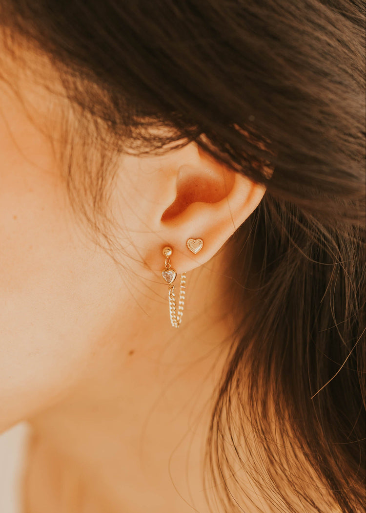 Close-up of an ear wearing gold hoop earrings with a blurred background