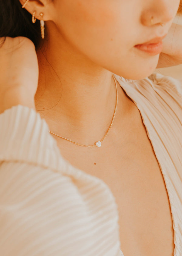 Close-up of a person wearing a delicate necklace with a small pendant.