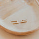 Gold earrings on a beige plate with a soft focus background