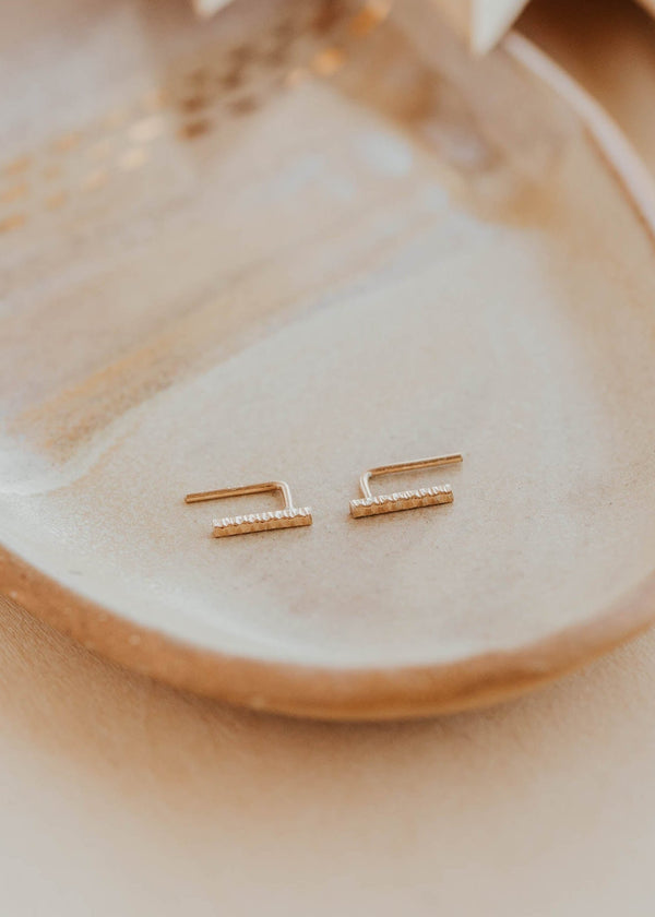 Gold earrings on a beige plate with a soft focus background
