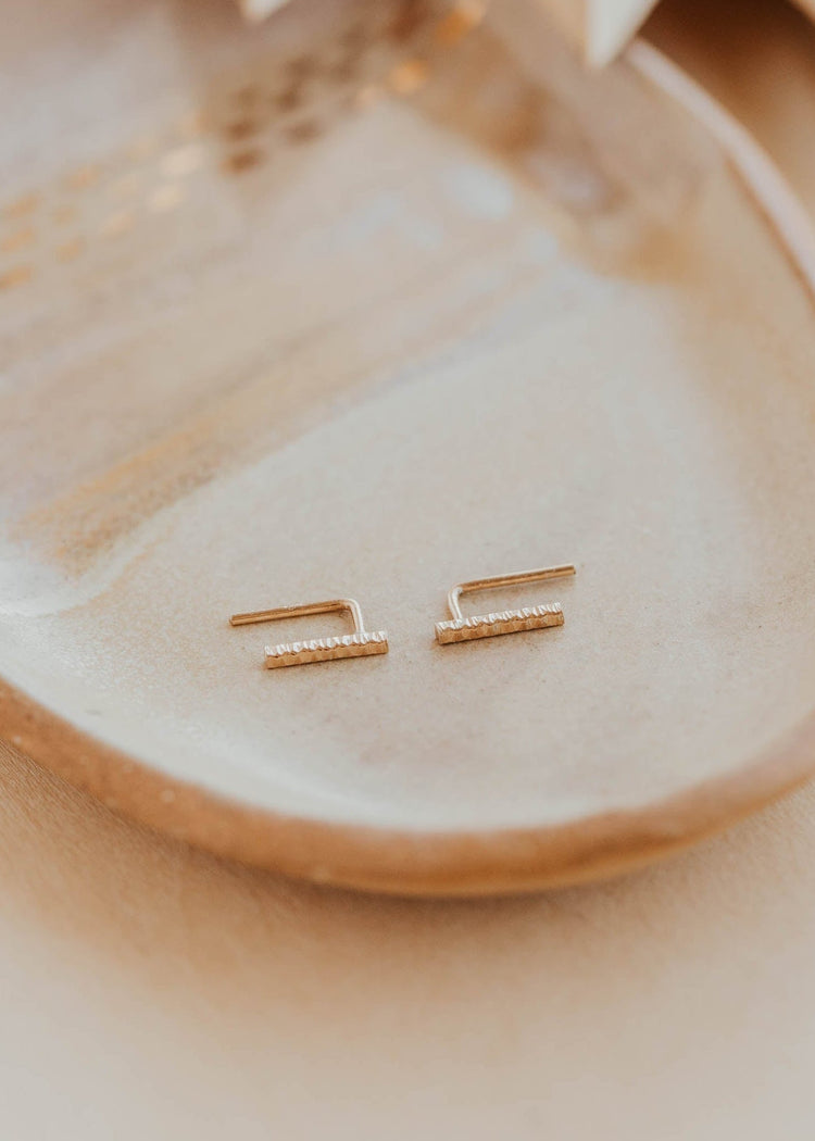 Gold earrings on a beige plate with a soft focus background