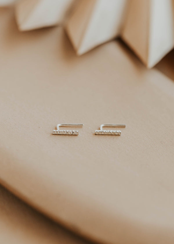 silver bar earrings on a beige fabric background