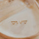 Gold earrings on a beige plate
