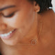 A charm necklace with a circle pendant attached to a gold chain necklace from Hello Adorn, a great layering necklace or statement necklace for a necklace layering idea.