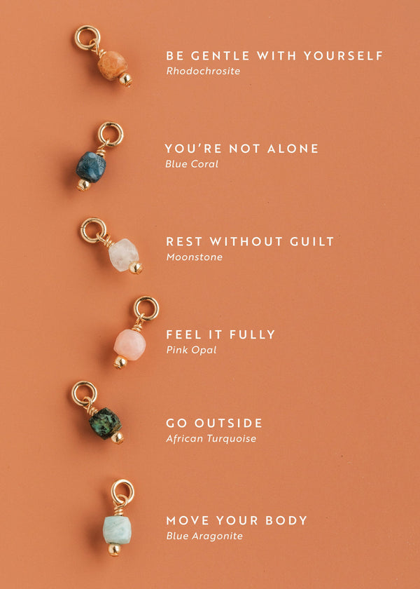 Set of Hello Adorn gemstone charms on a peach background with motivational mental health necklace phrases.