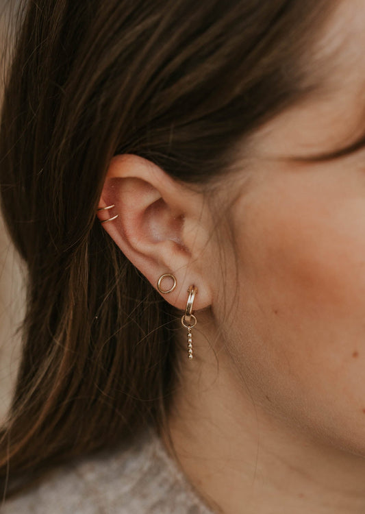 A pair of open circle earrings for everyday wear shown on a model in a stud earring style by Hello Adorn in 14k gold fill.