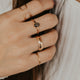 Close-up of a hand wearing multiple gold rings with a blurred background