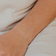 Silver bracelet on a wrist with a neutral background