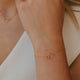Close-up of a person's wrist wearing a gold bracelet with a minimal background