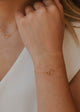 Close-up of a person's wrist wearing a gold bracelet with a minimal background