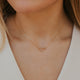 Close-up of a person wearing a delicate gold necklace with a small pendant.