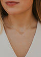 Close-up of a person wearing a delicate gold necklace with a small pendant.