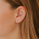 Close-up of an ear wearing a small earring with blonde hair.