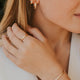 Close-up of a woman wearing gold jewelry including earrings, ring, and bracelet.