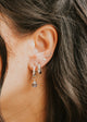 Close-up of an ear with multiple earrings against a blurred background