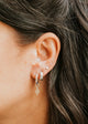 Close-up of an ear with multiple earrings and dark hair.