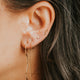 Close-up of an ear with gold earrings and dark hair.