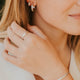 Close-up of a woman wearing silver hoop earrings, ring, and bracelet.