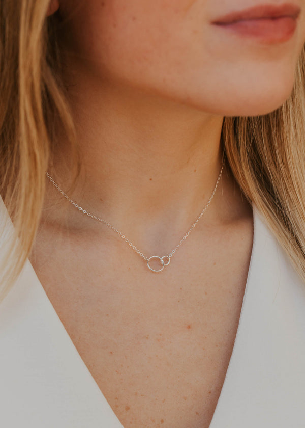 Close-up of a person wearing a delicate necklace with a small circular pendant.