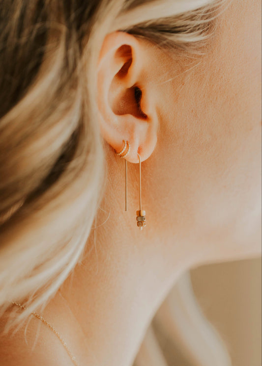 Close-up of a person wearing a gold earring with a blurred background