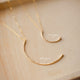 A statement necklace showing two crescent moon necklaces in the New Moon Pendant and Mini-Moon Pendant styles handmade by Hello Adorn, a hammered gold pendant attached to a dainty chain necklace.