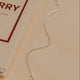 Silver bracelet on a beige surface with a book titled 'Book of Berry' in the background