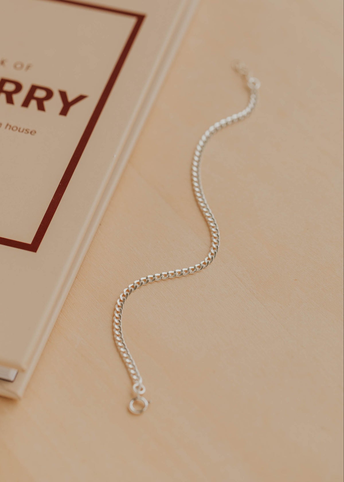 Silver bracelet on a beige surface with a book titled 'Book of Berry' in the background