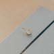 Gold pendant on a light blue card with a blurred background